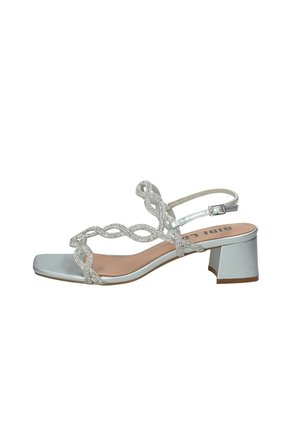 Sandalo argento con tacco basso a blocco, cinturini intrecciati con strass e fibbia regolabile alla caviglia, punta aperta e design frontale quadrato.