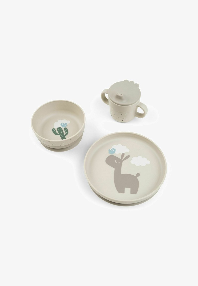 Set de table beige pour enfants avec une tasse à deux poignées, un bol avec un cactus et une assiette représentant un ours et un oiseau sous des nuages sur un fond blanc.