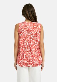 Ärmelloses Oberteil mit einem rot-weißen Blumenmuster, aus leichtem Stoff mit lässiger Passform und einem runden Ausschnitt.