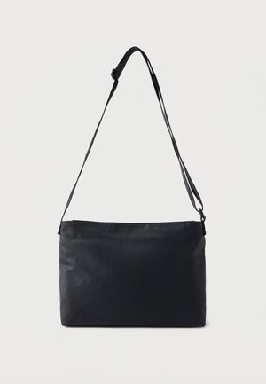 Czarna prostokątna torba na ramię z regulowanym paskiem na ramię, przedstawiona na jednolitym jasnym tle.