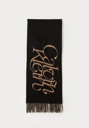 Fekete gyapjú sál, nagy világosbarna kalligrafikus logóval és bojt részletekkel az alsó szélen.