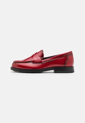 Rode glanzende leren loafer met zwarte zool, lage hak en bandje aan de voorkant, van opzij getoond op een witte achtergrond.