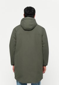 Parka isolée verte avec capuche, présentant une coupe droite, des manches longues et une texture lisse. Détails de coutures visibles.