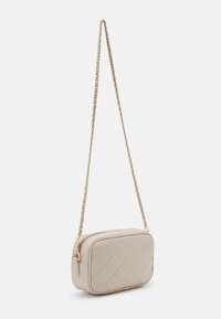 Sac bandoulière en cuir beige avec motif matelassé, forme rectangulaire, bandoulière chaîne dorée et fermeture éclair. Surface texturée pour plus de détails.