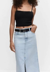 Crop top en tricot noir avec des bretelles fines, associé à une jupe midi en denim bleu clair avec une fente sur le devant et une ceinture noire avec une boucle en argent.