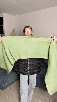 Φωτεινό πράσινο oversized πλεκτό πουλόβερ, με ραβδωτή υφή, κρατημένο μπροστά από ένα άτομο, σε στρώσεις πάνω από μαύρο μπουφάν, casual γκρι τζιν.