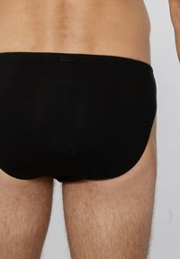 Zwarte zwemshorts van gladde stof, met ribbelstructuur, een elastische tailleband en een aansluitend ontwerp.