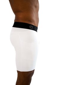 Pantaloni sportivi bianchi realizzati in tessuto liscio e elastico, con una vita elasticizzata nera che mostra un logo. Vista laterale ravvicinata.