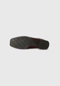 Brown leather shoe sole with a textured gray rubber outsole featuring a wavy pattern and a small heel. Brand name embossed on the side.