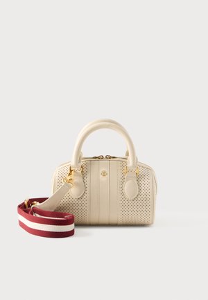 Crèmekleurige leren handtas met geperforeerde zijkanten, dubbele handvatten, gouden hardware en afneembare rood-wit gestreepte schouderriem op een witte achtergrond.