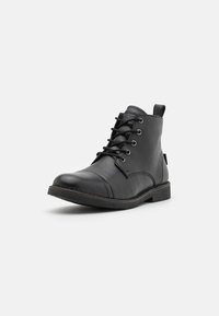 Black leather ankle boots with a rounded toe, lacing system, and textured surface. Features a low heel and side pull tab for easy wear.