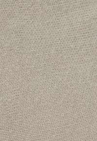 Bežová pletená vlněná látka s texturovaným vzorem malých, těsných smyček a mírně chlupatým povrchem.