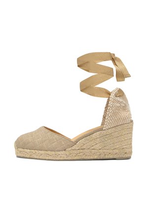 Zapato cuña espadrille beige con suela de yute trenzado y correa para atar alrededor del tobillo, empeine de tela texturizada y punta cerrada.