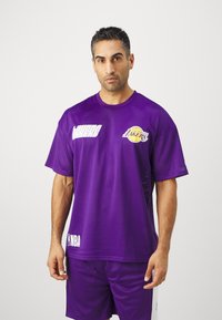 Camiseta de baloncesto de malla morada con mangas cortas, que presenta el logo de los "Lakers" y la marca de la NBA. Tela ligera y corte relajado.