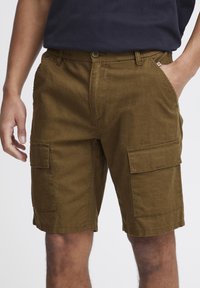 Cargo shorts i olivengrøn, lavet af et tekstureret stof. Har flere frontlommer, en knaplukning og en elastisk talje.