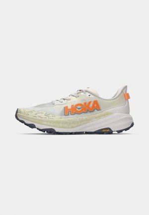 HOKA Laufschuh in Weiß und Gelb mit einem orangefarbenen Logo. Verfügt über ein strukturiertes Obermaterial, eine gepolsterte Mittelsohle und eine Vibram-Außensohle für Traktion.