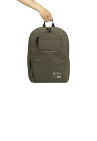Sac à dos vert olive avec un tissu texturé, deux poignées supérieures, une poche frontale, une fermeture éclair sur le côté et un logo sur le bas à l'avant.