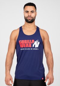 Navy tanktop gemaakt van sportstof, met rode en witte "GORILLA WEAR" tekst en een afbeelding. Gladde textuur, normale pasvorm.