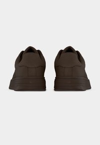 Καφέ αθλητικά παπούτσια με λείο υφασμάτινο επάνω μέρος, στρογγυλεμένη μύτη, επενδυμένο περιλαίμιο και υφασμένη σόλα από καουτσούκ. Διαθέτουν μινιμαλιστικό σχέδιο.