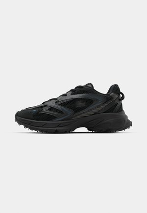 Zapatillas deportivas negras con parte superior de malla y superposiciones sintéticas. Suela texturizada para tracción. Cuenta con cordones y una lengüeta en el talón.