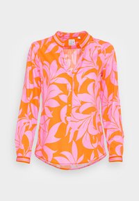 Blouse fleurie avec un fond orange vif, des motifs de feuilles roses, une fermeture à boutons sur le devant et un col sans col avec des accents rayés.