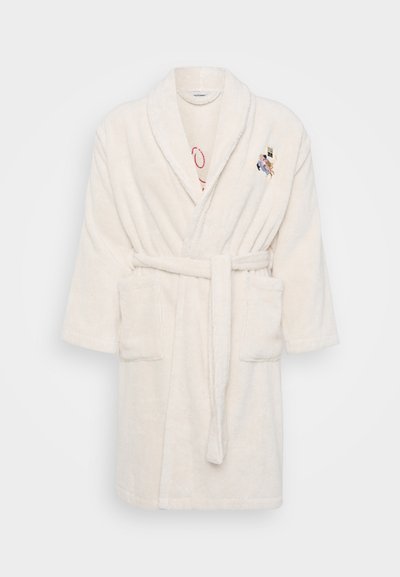 White terry cloth bathrobe with a tie belt, short sleeves, two front pockets, and an embroidered detail on the chest. Soft, textured fabric.