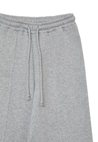 Pantaloni sportivi grigi con elastico in vita, dotati di cordino con tasselli, texture morbida e dettagli sulle cuciture laterali.