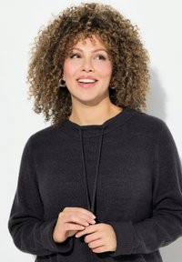 Maglione grigio scuro a maglia con scollatura rotonda, dettaglio con cordino e polsini a coste, caratterizzato da una texture morbida e una vestibilità rilassata.