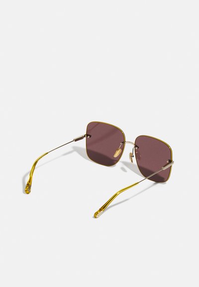 Ochelari de soare pătrați cu ramă din metal aurie, lentile burgundii închise, brațe subțiri și suporturi pentru nas pentru confort. Design minimal și ușor.