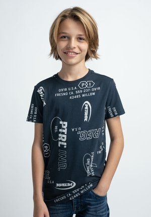 Mørkeblå t-shirt lavet af bomuld, med forskellige hvide teksttryk og logoer i flere stilarter over hele stoffet. Kortærmet og rund hals.