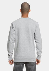 Sudadera gris de manga larga, con puños y dobladillo acanalados, hecha de material suave. Presenta un diseño liso sin logotipos ni patrones visibles.