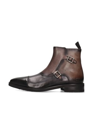 Botas de tobillo de cuero marrón con un acabado suave, punta afilada, dos hebillas plateadas y un diseño texturizado. Suela de goma negra sólida.
