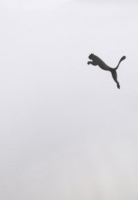 Baltas medvilnės marškinėliai su juodu šuoliuojančio Puma logotipu kairėje krūtinės pusėje. Audinys turi lygią tekstūrą ir klasikinį apvalų iškirpimą.