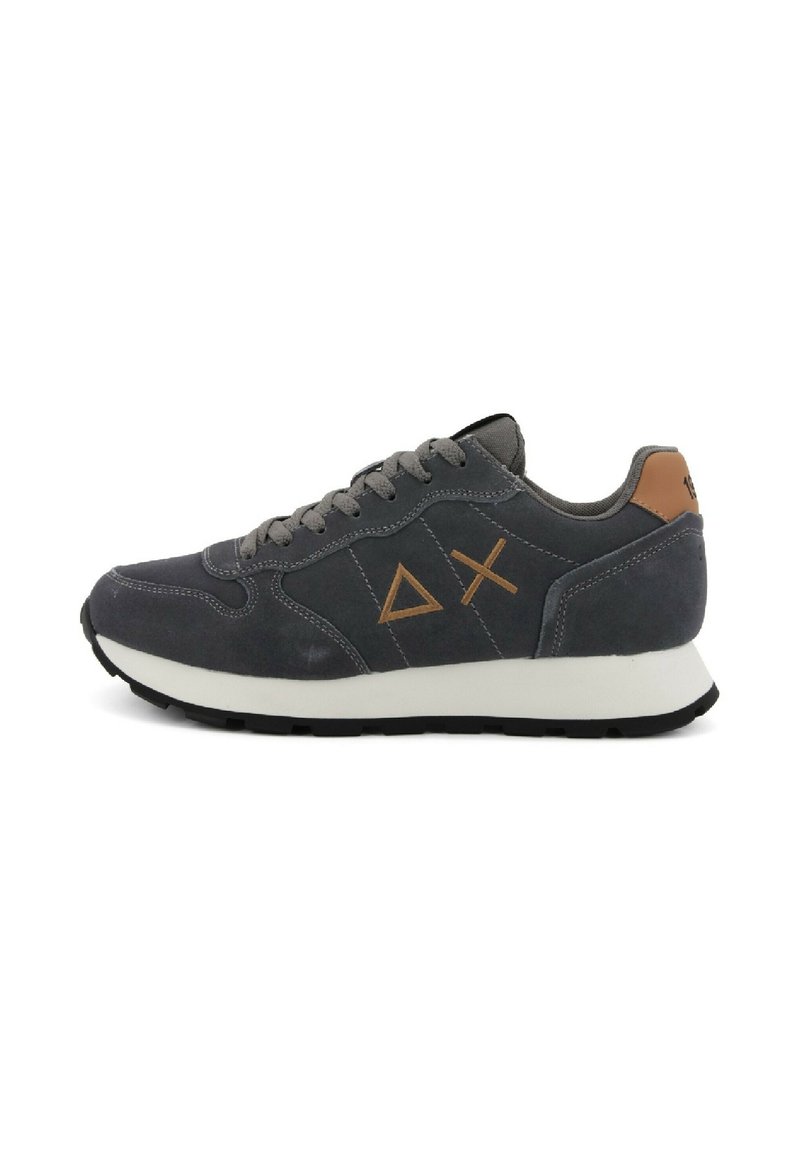 Sneaker in suede grigia con una suola bianca, presenta un accento in pelle marrone sul tallone e un design con forme geometriche sul lato.