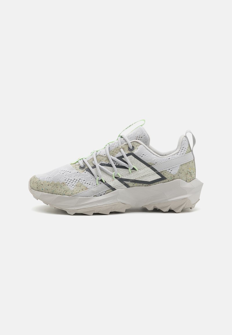Sapatos de corrida em trilhos feitos de malha branca com detalhes em verde e cinza. Apresentam uma sola texturizada e um design geométrico irregular para tração.
