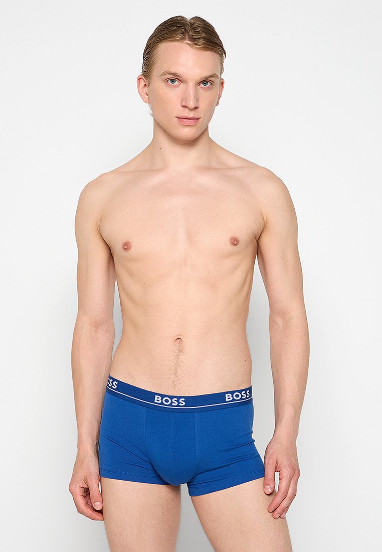 Boxers en coton bleu avec une coupe ajustée. Présentent une ceinture de marque avec des accents de couleur contrastés. Texture lisse, longueur mi-thigh.