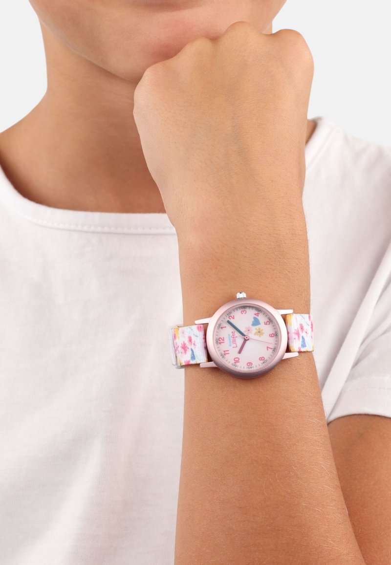 Bunte Kinderuhr mit einem blumigen Stoffarmband, pinkem rundem Ziffernblatt und leicht ablesbaren Zahlen. Silberne Hardware-Akzente.