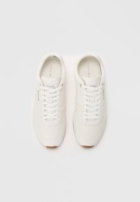 Adidași albi cu un exterior din piele netedă, vârf rotund, talpă din cauciuc și șireturi plate. Prezintă logo-ul brandului pe lateral și pe limbă.