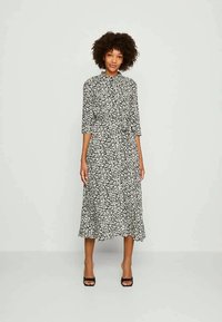 Rochie cu imprimeu floral alb-negru, cu guler, mâneci trei sferturi și fustă evazată. Fabricată dintr-un material ușor, cu o croială lejeră.