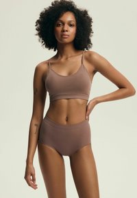Brązowy stanik typu bralette z żeberkowaniem i majtki w wysokim stanie. Miękki materiał, regulowane ramiączka i gładka tekstura. Brak wyraźnych wzorów lub dodatków.