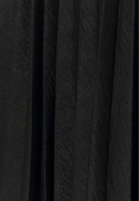 Svart plisserad tyg med en texturerad yta, med vertikala veck som skapar djup och rörelse, vilket framhäver en slät yta.