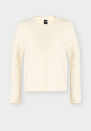 Pull texturé crème à manches longues et col rond avec une étiquette de la marque BOSS à l'intérieur du col, présenté sur un fond gris uni.