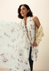 Viegls balts šalle ar atkārtotiem ilustrētu brillīšu un lokiņu motīviem gaiši zils un zelta akcentos. Mīksta auduma tekstūra.