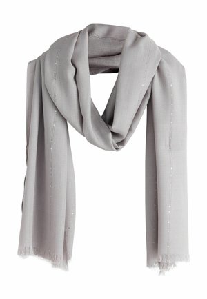 Kobieta w żółtej sukni z koronkową lamówką i jasnoszarym szalem zawiązanym na ramionach, z dodatkami w postaci złotej bransoletki i kolczyków.