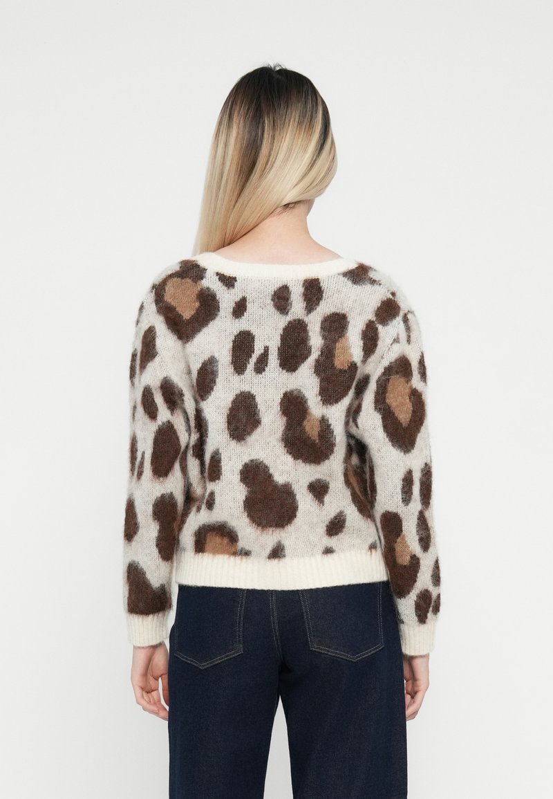 Sweter dziewiarski z kremowym podkładem i brązowymi cętkami w ludzkie cętki, okrągłym dekoltem, długimi rękawami oraz ściągaczem na dole. Miękka, teksturowana tkanina.