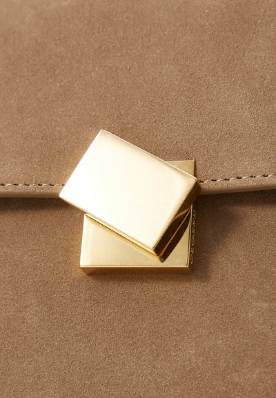 Brun ruskind taske med en glat guld rektangulær clasp, der har et lagdelt design. Syede detaljer komplementerer den minimalistiske stil.
