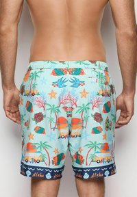Un short de bain avec une base bleu clair et un motif tropical vibrant, comprenant des poissons, des palmiers et des éléments de plage. Taille élastique.