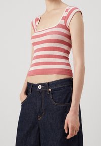 Červený a růžový pruhovaný žebrovaný crop top se čtvercovým výstřihem a krátkými rukávy, spárovaný s tmavě modrými džínami s vysokým pasem a předními kapsami.