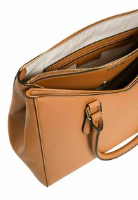 Borsa a mano in pelle color tan con superficie testurizzata, zip dorata e scomparti interni. Presenta un manico corto e un design elegante e strutturato.