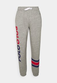 Grå sweatshirtbyxor med dragsko i midjan, med "POLO" i rött på vänster ben och marinblå och röda ränder nära muddarna. Mjuk textur.